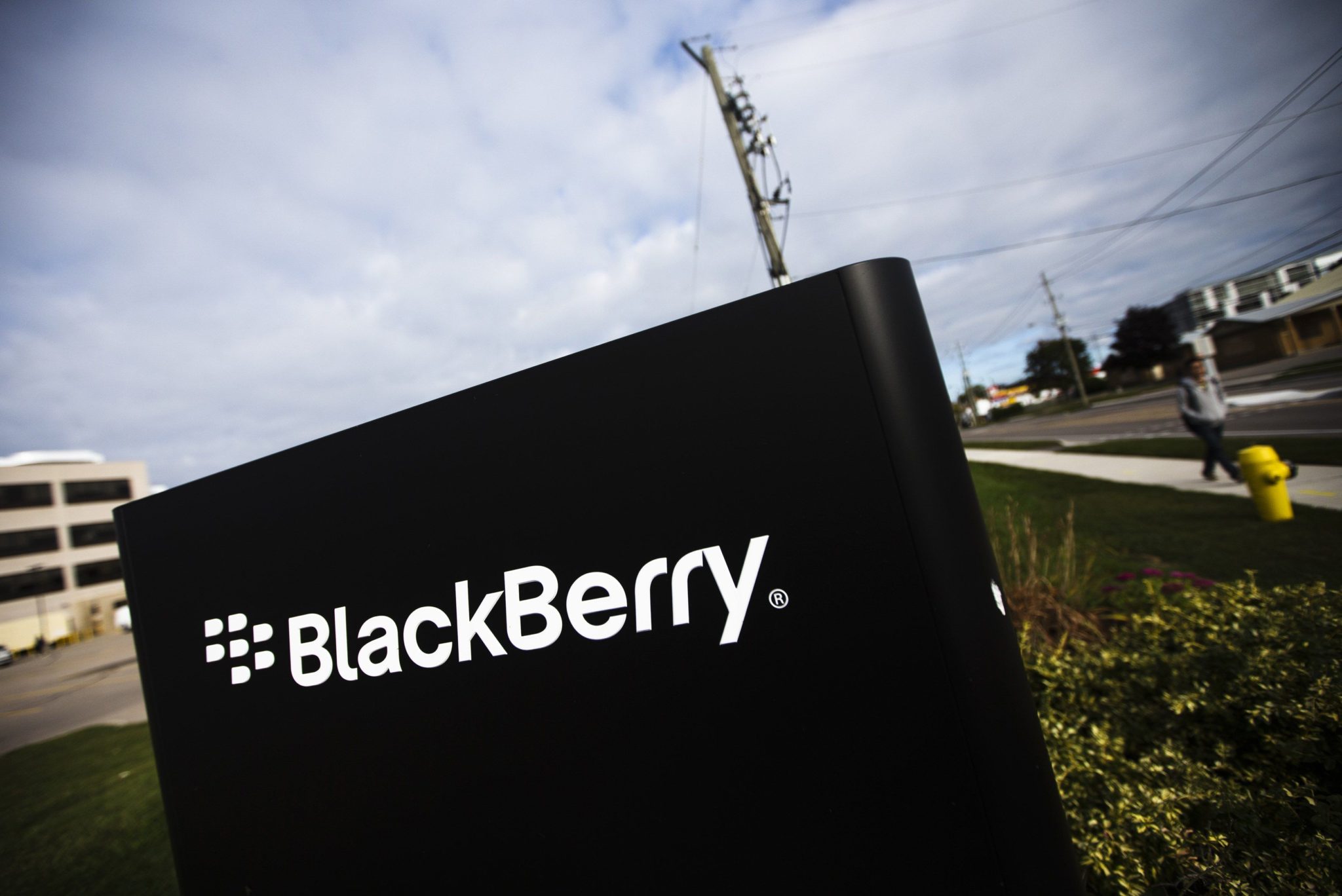 A man walks by a Blackberry sign at the Blackberry campus in Waterloo, September 23, 2013. Struggling smartphone maker BlackBerry on Monday signed a tentative deal to be acquired by a consortium led by its biggest shareholder, setting a $4.7 billion floor in the auction of the Canadian company that invented on-the-go email.   REUTERS/Mark Blinch (CANADA - Tags: BUSINESS SCIENCE TECHNOLOGY)