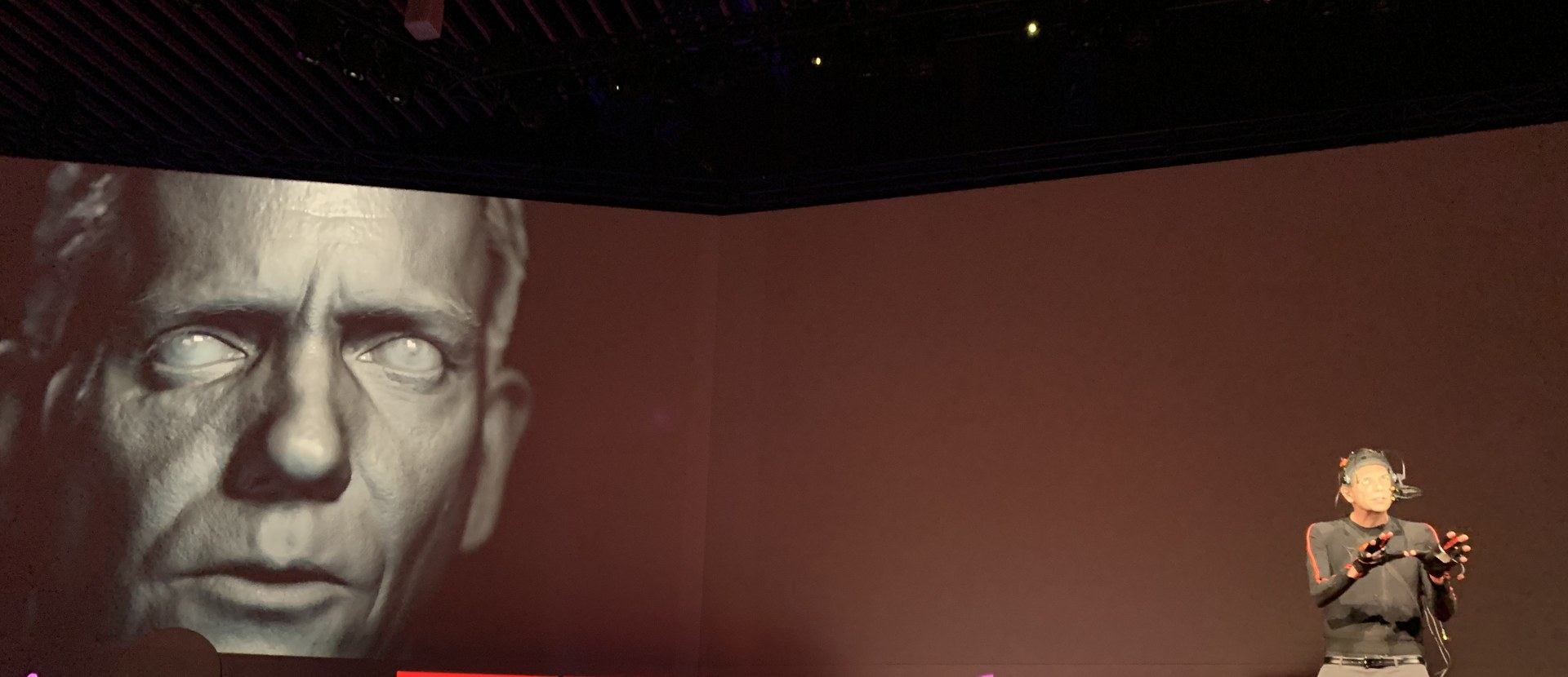 عرض تجريبي لوجه مولد بتقنية الديب فيك على شاشة ضخمة في مؤتمر TED