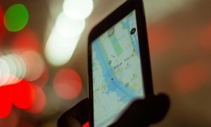 صورة توضيحية: شخص يمسك هاتفًا يعرض خريطة GPS (Enrique Alarcon / Unsplash)